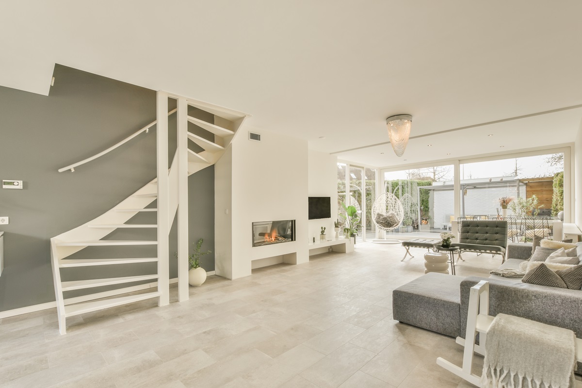 Contemporary minimalist style interior design of light studio apartment with wooden table and chairs in dining zone between open kitchen and living room with white walls and parquet floor