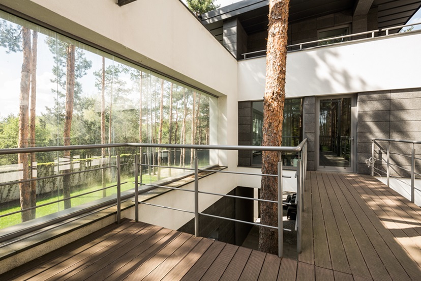Big house in the forest with terrace and tree growing inside the house